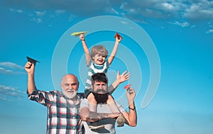 Father son and grandfather relaxing together. Freedom to dream - joyful kid playing with airplane against the sky -