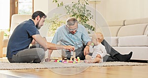 A father with son and grandson spend family time together, stacking blocks on the carpet.