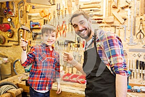 Father and son with hammers working at workshop