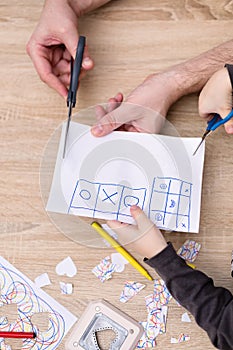 Father and son hands cutting paper with scisors