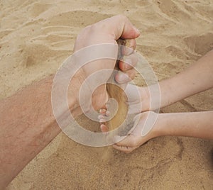 Father and son hands on sand. Close up