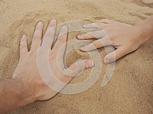 Father and son hands on sand. Close up