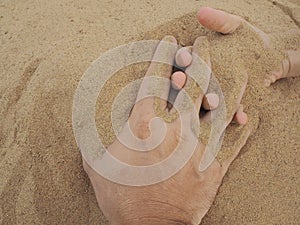 Father and son hands on sand. Close up