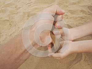 Father and son hands on sand. Close up