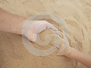 Father and son hands on sand. Close up