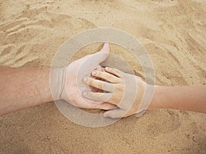Father and son hands on sand. Close up