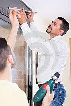 Father and son hanging curtain rod photo