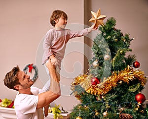 Father, son and happy with bonding by christmas tree for celebration and playing with star in the morning. Family, man