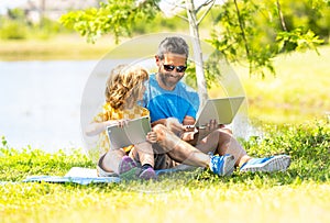 father and son have online education outdoor. Pupil with teacher studying online and work on tablet in park. dad and kid