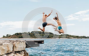 Father and son having a fun on a merry vacation days on ocean coast. They dressed swimming trunks jumping to the waives from the