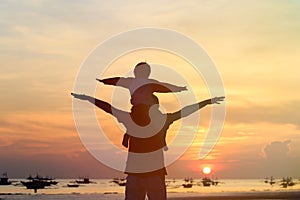 Father and son having fun on sunset beach