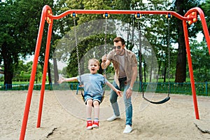 father and son having fun on swing at playground