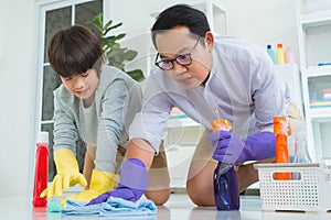 Father and son having fun wiping and cleaning the floor together with cleaning liquid agent and colorful towels for family