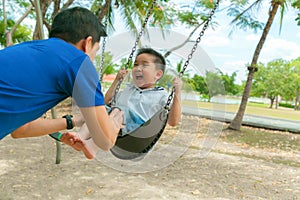 Father and son having funny on swing in playground