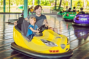 Father and son having a ride in the bumper car at the amusement park