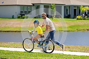 Father and son in a helmet riding bike. Little cute adorable caucasian boy in safety helmet riding bike with father