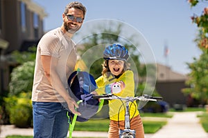 Father and son in a helmet riding bike. Little cute adorable caucasian boy in safety helmet riding bike with father