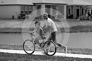 Father and son in a helmet riding bike. Little cute adorable caucasian boy in safety helmet riding bike with father