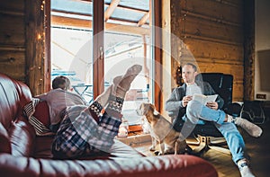 Father, son and his beagle dog spending holiday time in cozy country house. Dad reading a book, boy lying and listening, dog