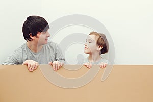 Father and son holding cardboard billboard together. Father and child looking at each other