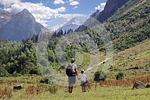 Father and son holding hands look at amazing mountain landscape