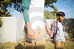 Father and son holding hands during sunny day