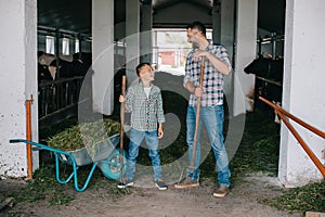 father and son holding pitchforks and smiling each other while working together