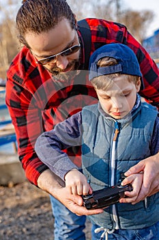 Father and son holding remote control joystick and piloting quadrocopter