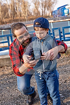 Father and son holding remote control joystick and piloting quadrocopter