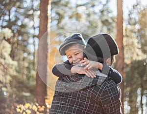 Father and son hugging and embrace in forest. Happy dad and child boy enjoying autumn time on vacation in a sunny park. Kids love