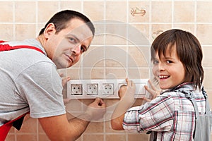 Father and son installing electrical wall fixtures