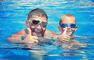 Father and son jump and swim in the pool under sun light at summer day. Leisure and swimming at holidays.