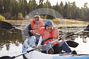 Father and son kayaking on a rural lake, front view