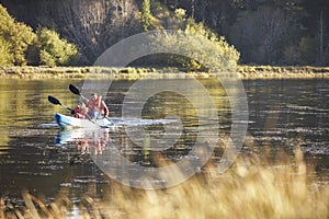 Father and son kayaking together on a lake, front view