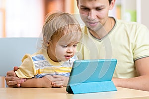 Father and son kid play with tablet computer indoors
