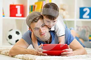 Father and son kid play with tablet computer