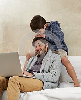 Father, son and laptop on sofa with love, playing and happiness for bonding in living room of home. Family, man and