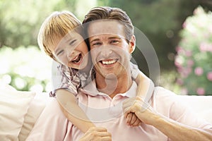 Father With Son Laughing Together On Sofa