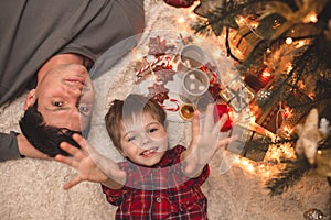 Father and son laying under christmas tree.