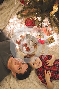 Father and son laying under christmas tree.