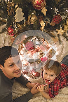 Father and son laying under christmas tree.