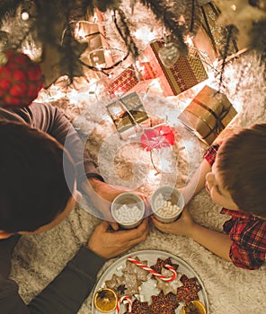 Father and son laying under christmas tree.