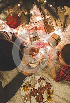 Father and son laying under christmas tree.