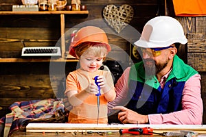 Father and son learning use carpenter tools. Boy with dad building wooden house together. Fatherhood concept.