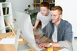 father and son looking at computer