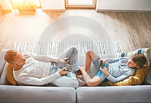 Father and son Losted in electronic devices. They playing with tablet and gamepad sitting in living room photo