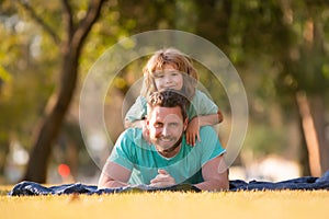 Father and son lying on grass. People having fun outdoors. Concept of happy vacation and friendly family.