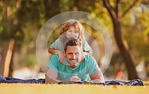 Father and son lying on grass. People having fun outdoors. Concept of happy vacation and friendly family.