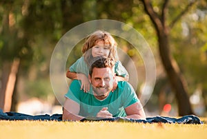 Father and son lying on grass. People having fun outdoors. Concept of happy vacation and friendly family.
