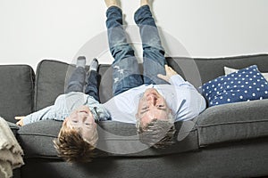 Father and son lying upside down on sofa